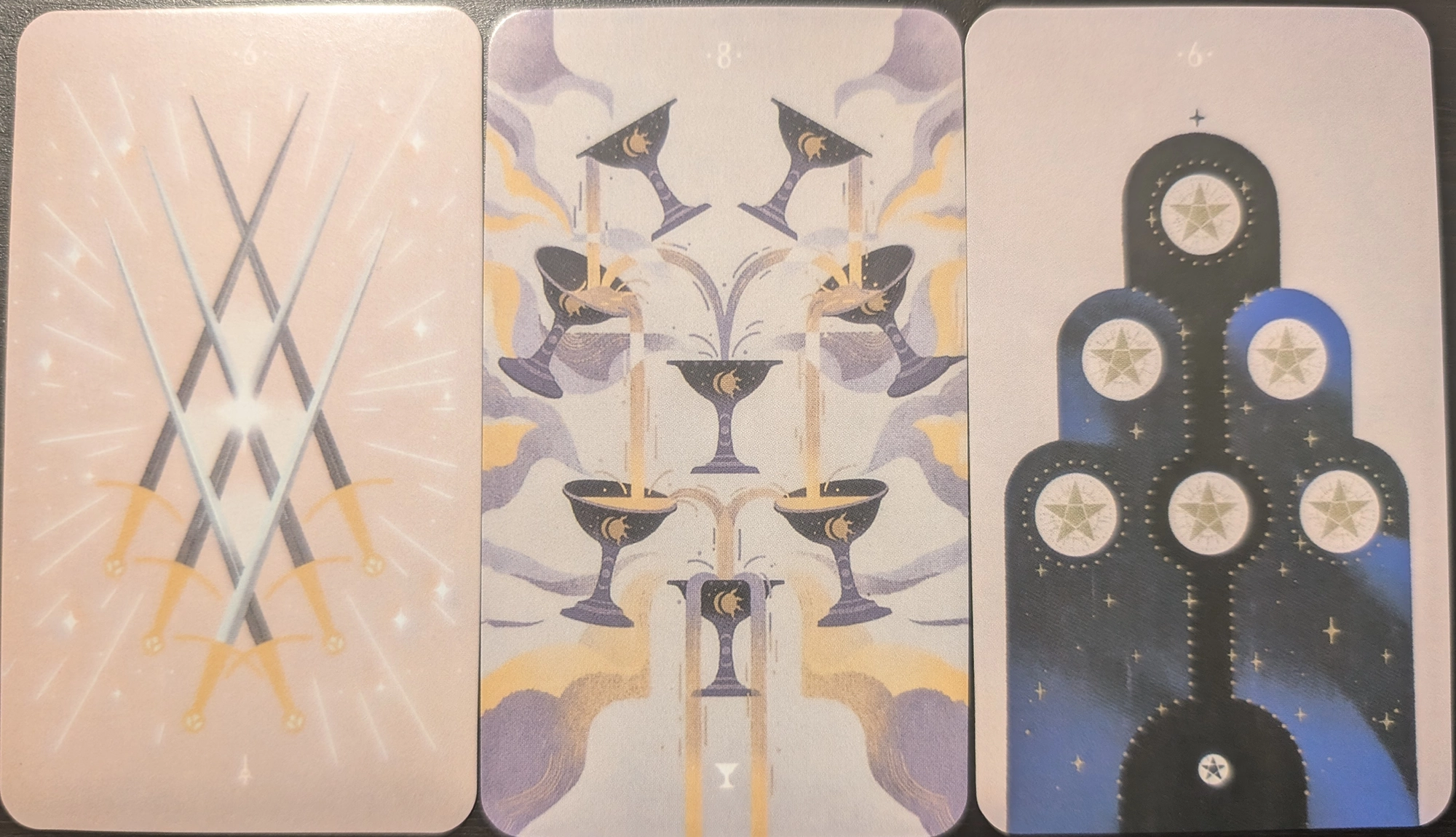 3 cards from the Spheres of Heaven tarot of the 6 of swords, 8 of cups, and the 6 of pentacles.