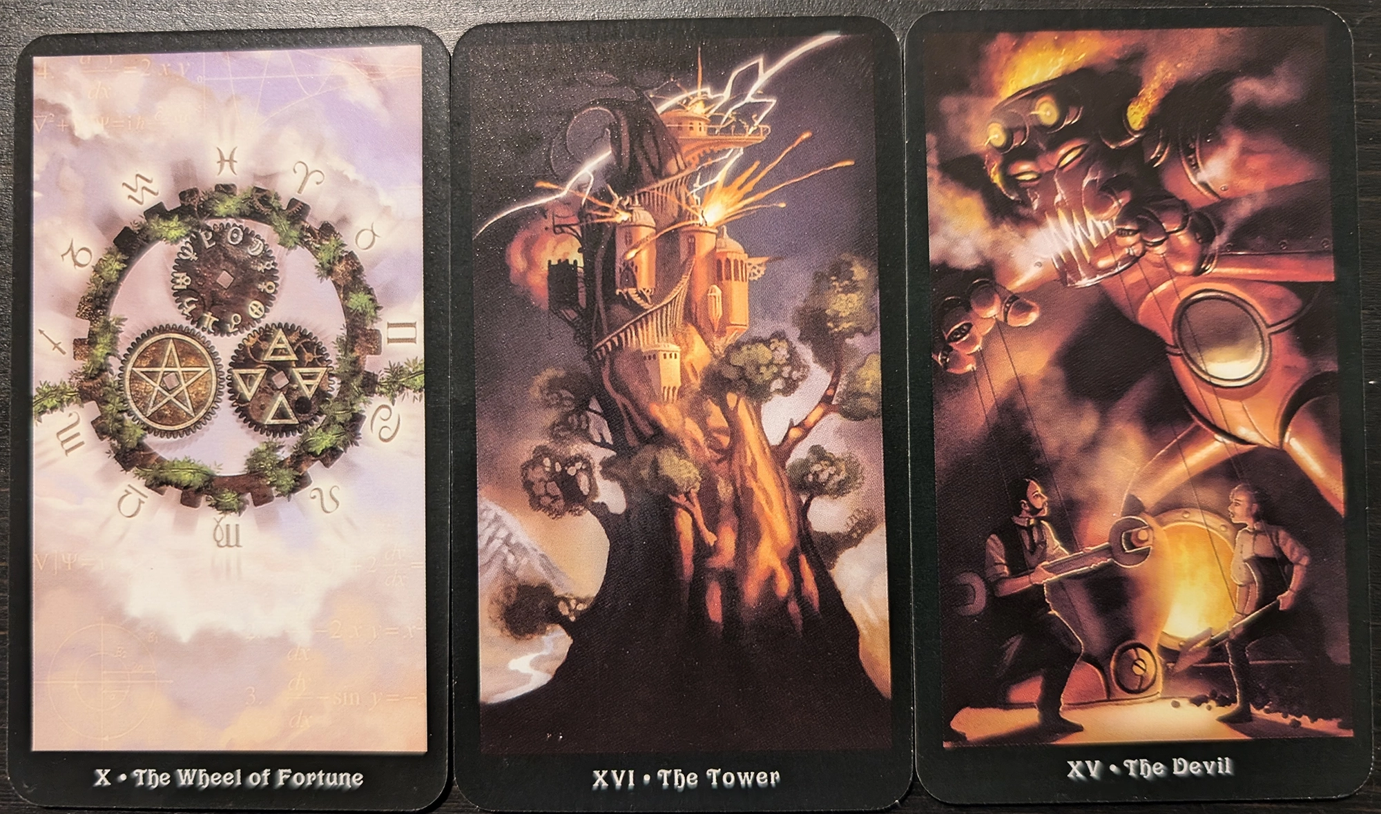 3 cards from the Steampunk Tarot of the WHeel of Fortune, The Tower, and The Devil. 