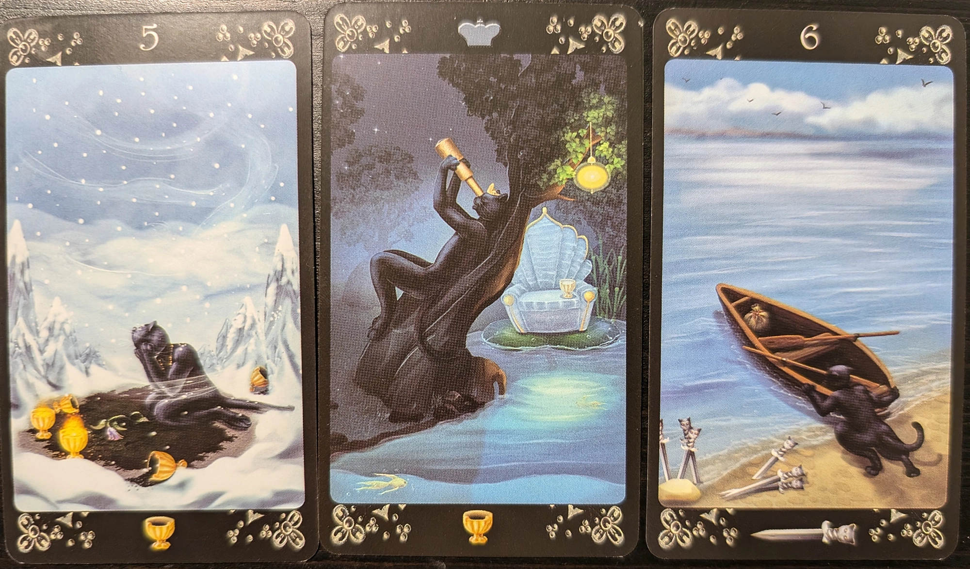 3 cards from the Black Cats tarot of the Five of Cups, the Queen of Cups, and the Six of Swords