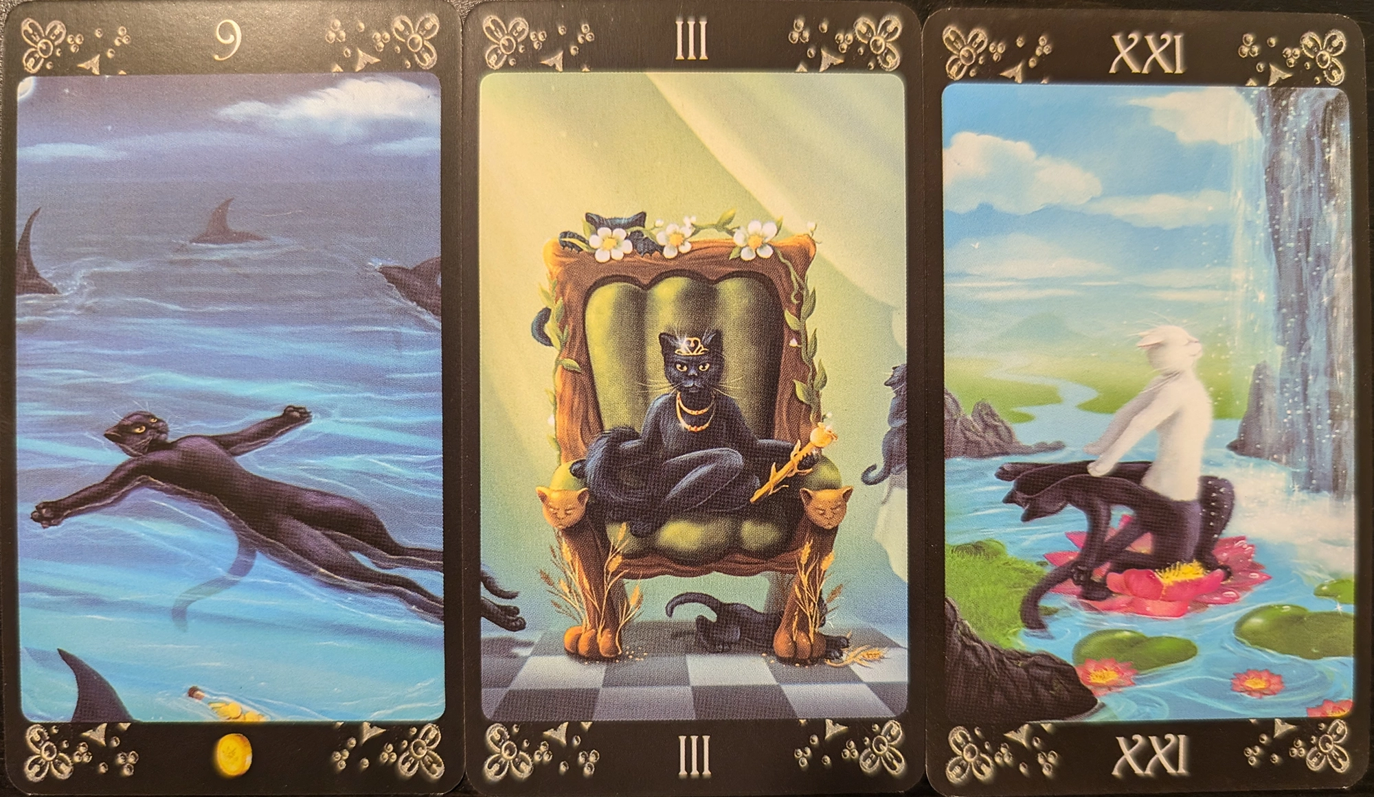 3 cards from the Black Cats tarot of the Nine of Pentacles, The Empress, The World