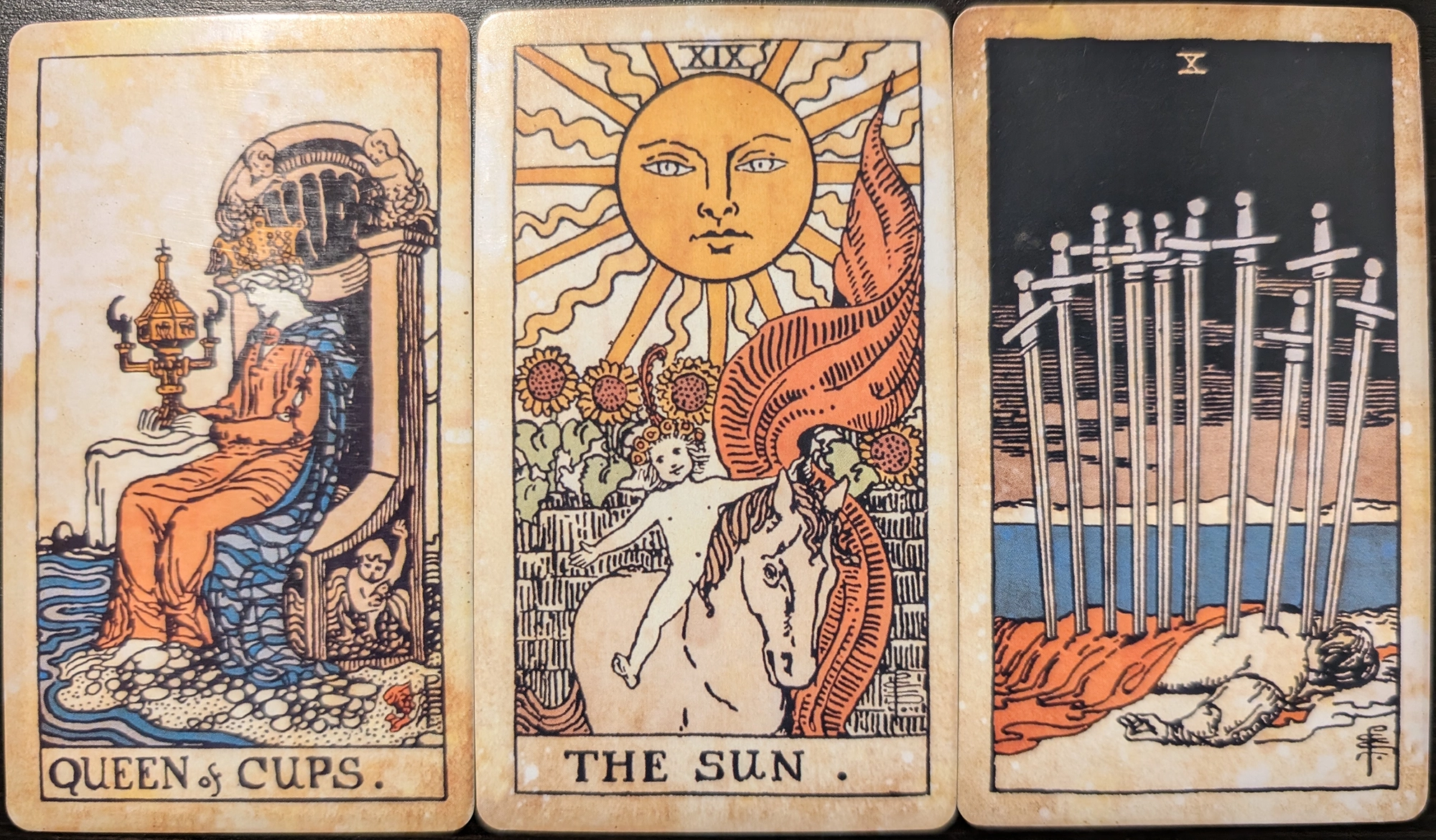 3 cards from the Vintage Tarot of the Queen of Cups, The Sun, Ten of Swords. 